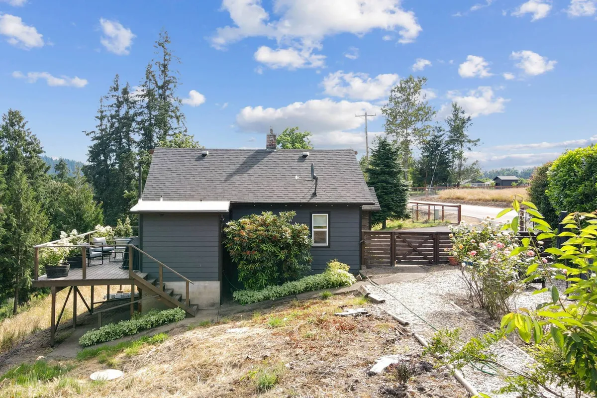 A tranquil exterior shot of the cottage's deck, surrounded by flowering plants and lush greenery. The deck offers a comfortable vantage point for enjoying the views, relaxing outdoors, or savoring the fragrance of blooming flowers. The pathway invites guests to step out and explore the countryside.