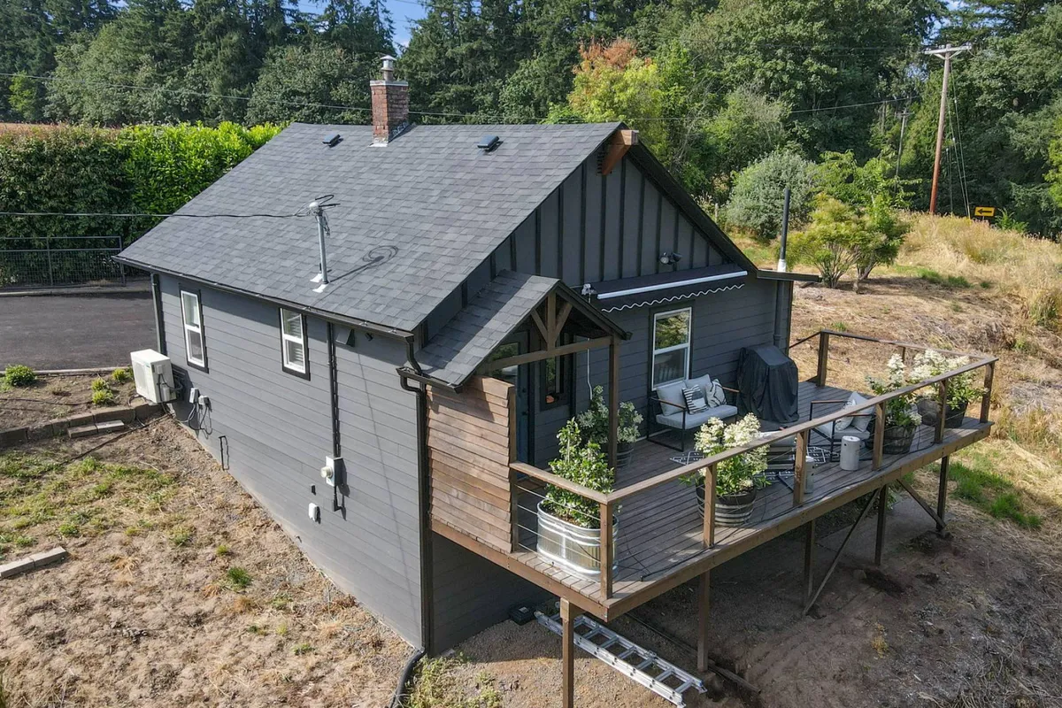 A spacious deck area with comfortable seating, accented by decorative plants and a view of the cottage's exterior architecture. The setting is ideal for outdoor family meals, gatherings, or unwinding in the fresh air.