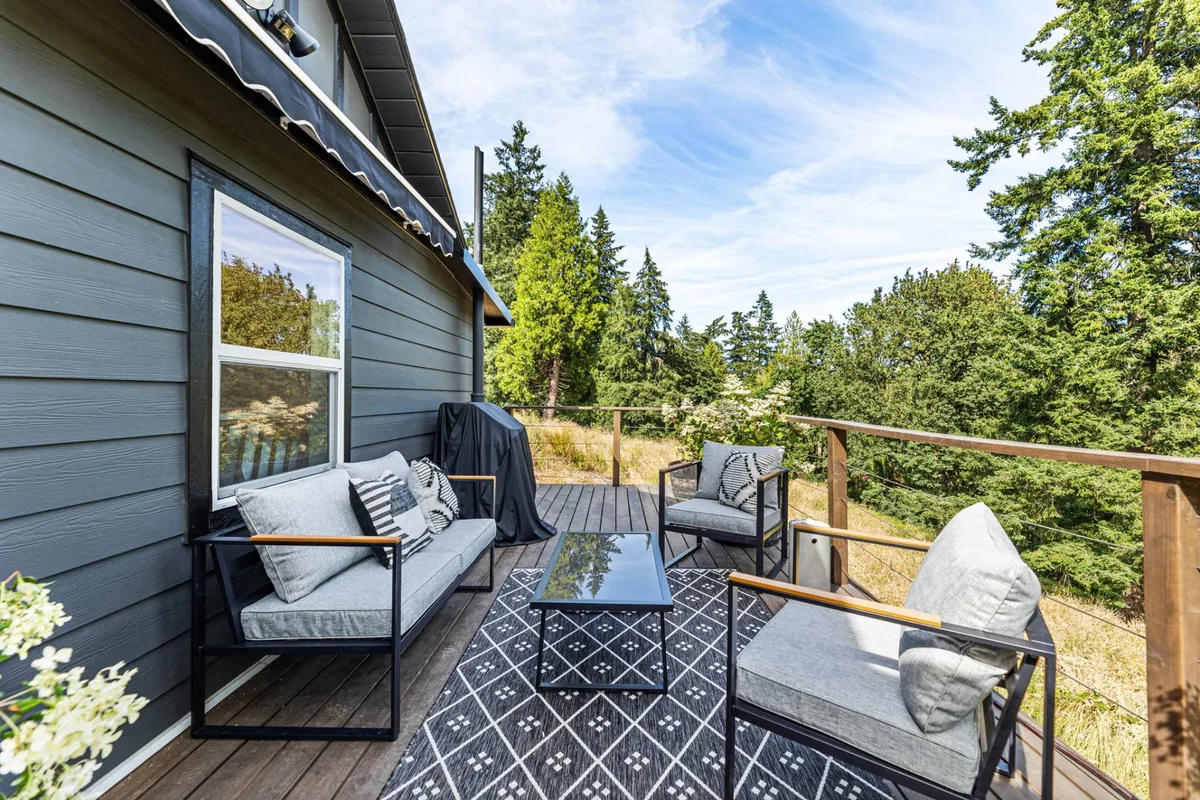 A serene outdoor seating area with a coffee table, surrounded by lush greenery and dappled sunlight. The tranquil setting is ideal for relaxing after a day of wine tasting, with sunset views creating a peaceful atmosphere.